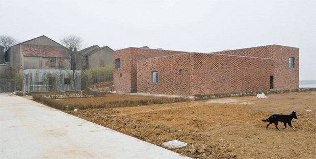 The two neighbouring houses are made from concrete slabs clad in local red bricks  