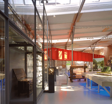 The bridge passing through the museum hall, with the display cases to the left. Wooden patches on the ceiling mark holes caused by falling debris after the fireworks explosion