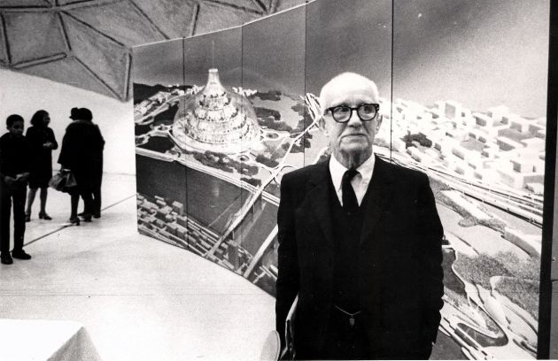 R. Buckminster Fuller stands in front of a depiction of his domed city design at its first public showing at a community meeting in East St. Louis Illinois. Photo by Steve Yelvington via Wikimedia